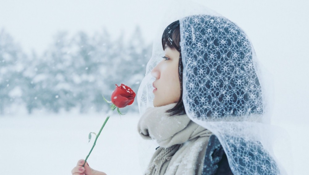 雪の中薔薇をもっている女性